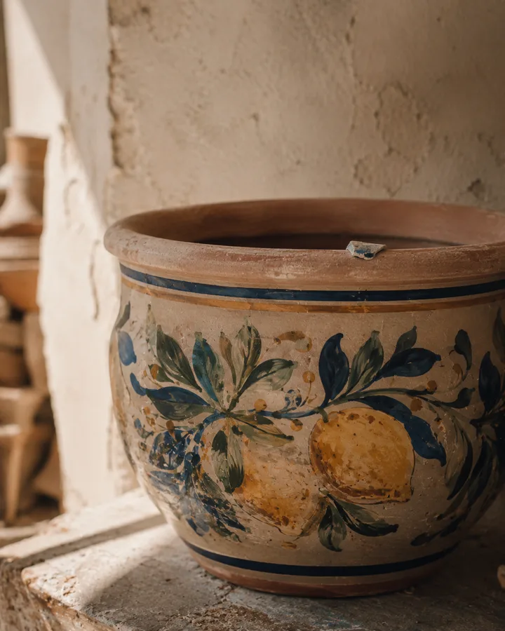 Close detail of an Elena-painted citrus-and-leaf terracotta planter.