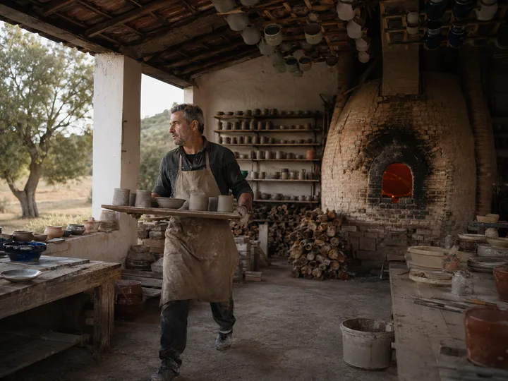 Wide view of Forno do Vale studio in the Alentejo, with the wood-fired kiln glowing warm and drying racks of mugs.