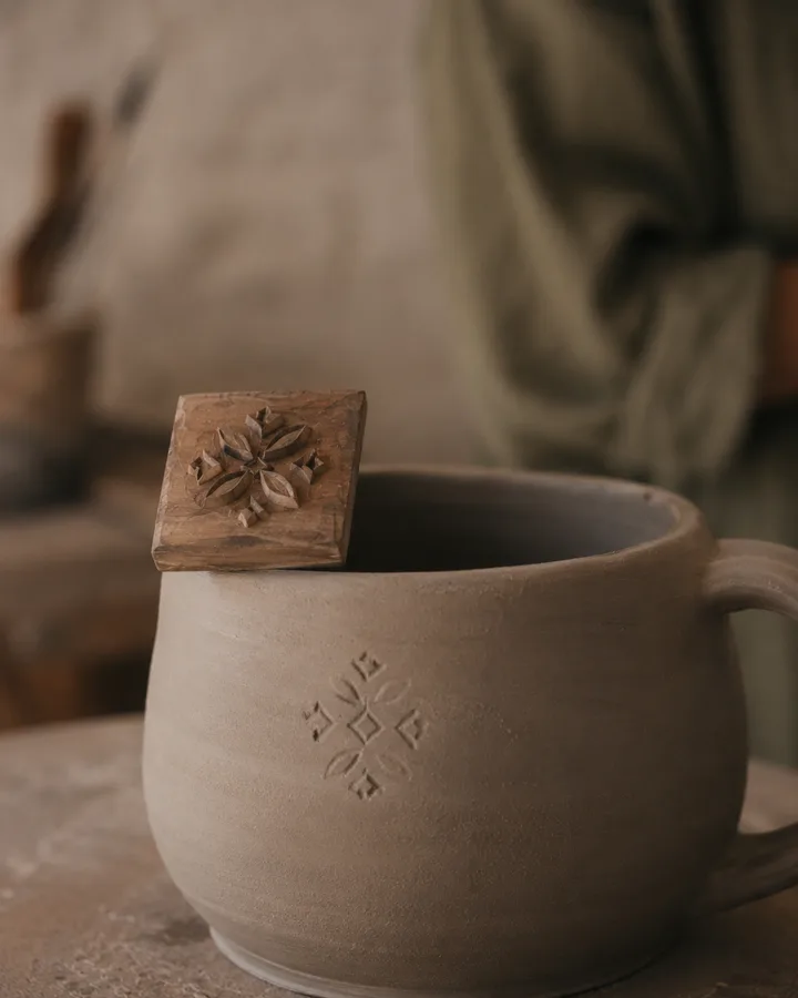 Carved wooden stamp resting on the rim of a freshly-trimmed mug at Zoé's studio.